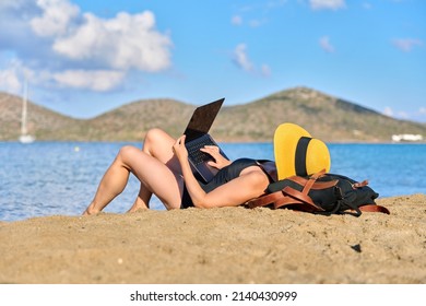 Mature Woman Sunbathing On The Beach Using A Laptop