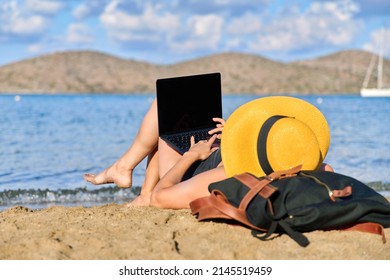 Mature Woman Sunbathing On The Beach Using A Laptop