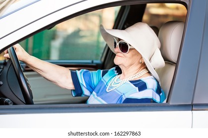 Mature Woman In Sunglasses Driving Automobile .