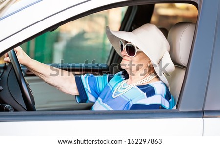 mature woman in sunglasses driving automobile .