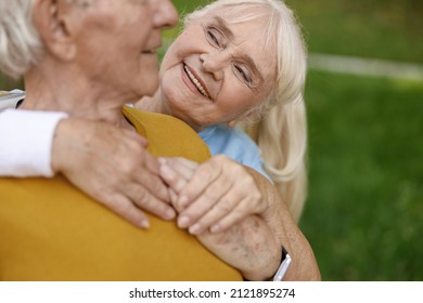 Mature woman sweatband hugs partner training together in green park