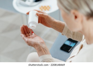 Mature Woman Taking Medicine Sitting On The Couch .