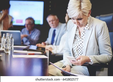 Mature Woman Taking Picture Of Documents At Work 
