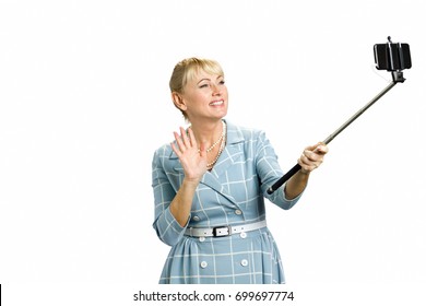 Mature Woman Taking Video With Monopod. Attractive White-skin Lady Waving With Hand And Smiling To Selfie Stick In Studio.