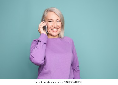 Mature Woman Talking On Mobile Phone Against Color Background