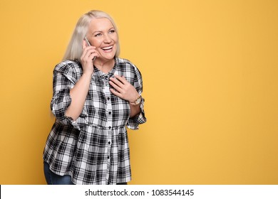 Mature Woman Talking On Mobile Phone Against Color Background