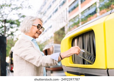 mujer madura lanzando plástico a la papelera de reciclaje