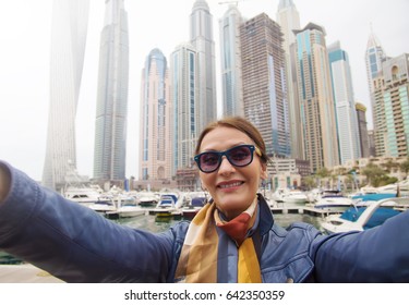 Mature Woman Tourist Laughing And Taking Selfie Photo In Dubai Marina,Dubai,United Arab Emirates.Female Traveler And Photographer Takes Picture For Her Blog.Cheerful Happy Tourist Making Selfie Photo 