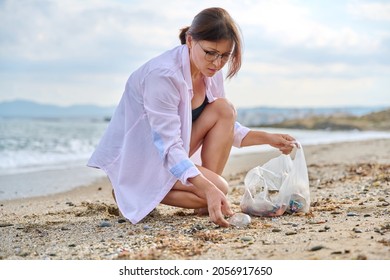 Mature Woman Tourist Relaxing On The Beach Collecting Plastic Trash In A Bag