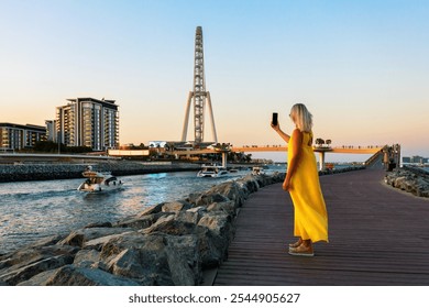 Mature woman tourist in yellow dress in Dubai marina taking selfie.  - Powered by Shutterstock