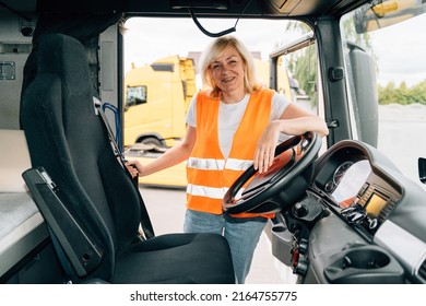 Mature Woman Truck Driver Steering Wheel Inside Lorry Cabin. Happy Middle Age Female Trucker Portrait 