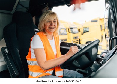 Mature Woman Truck Driver Steering Wheel Inside Lorry Cabin. Happy Middle Age Female Trucker Portrait 