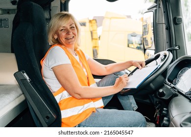 Mature Woman Truck Driver Steering Wheel Inside Lorry Cabin. Happy Middle Age Female Trucker Portrait 