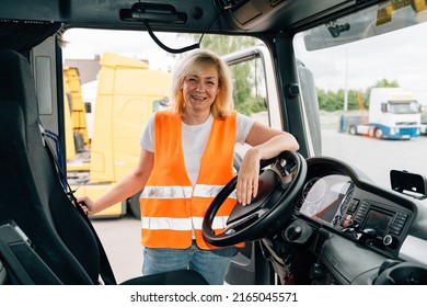 Mature Woman Truck Driver Steering Wheel Inside Lorry Cabin. Happy Middle Age Female Trucker Portrait 