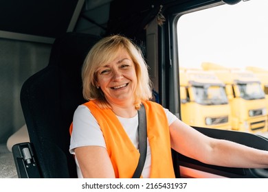 Mature Woman Truck Driver Steering Wheel Inside Lorry Cabin. Happy Middle Age Female Trucker Portrait 