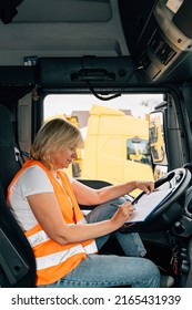 Mature Woman Truck Driver Steering Wheel Inside Lorry Cabin. Happy Middle Age Female Trucker Portrait 