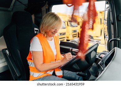 Mature Woman Truck Driver Steering Wheel Inside Lorry Cabin. Happy Middle Age Female Trucker Portrait 