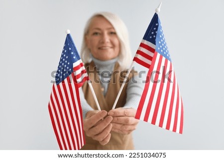 Mature woman with USA flags on grey background, closeup
