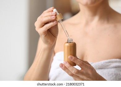 Mature Woman Using Cosmetic Serum In Bathroom, Closeup