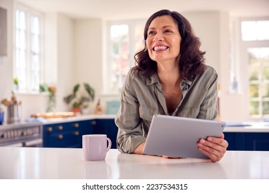 Mature Woman With Using Digital Tablet At Home To Book Holiday Or Shop - Powered by Shutterstock