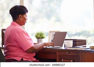 Mature Woman Using Laptop On Desk At Home