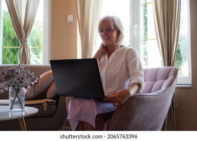 A Mature Woman Is Using A Laptop For Online Consultation With Her Doctor In A Video Call.