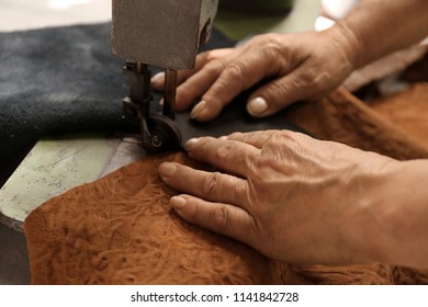 Mature woman using sewing machine in leather workshop, closeup - Powered by Shutterstock