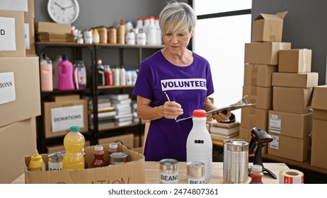 Mature woman volunteering in a warehouse, organizing food donations indoors. - Powered by Shutterstock