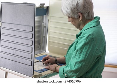 Mature Woman Voting At A Booth, Ballot Casting