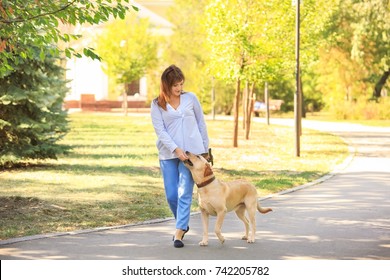 Mature Woman Walking Her Dog In Park