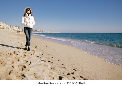 Mature Woman Walking On The Beach On A Sunny Winter Day