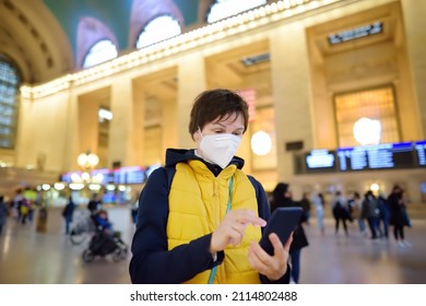 Mature Woman Wearing A Face Mask Is Using Her Phone To Buy A Ticket Online In Grand Central Station New York, Manhattan. Female Tourist Plans A Trip By Her Smartphone. Travel And Tourism In Usa.