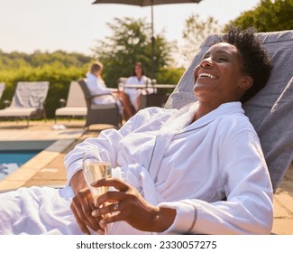 Mature Woman Wearing Robe Outdoors On Lounger Drinking Champagne On Spa Day - Powered by Shutterstock