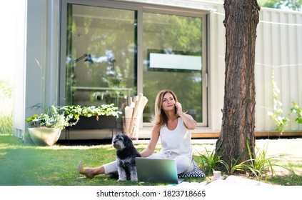 Mature woman working in home office outdoors in garden, using laptop.