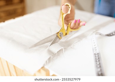 A mature woman works diligently as a designer, skillfully cutting fabric with golden scissors in her creative office environment. She focuses on her craft, showcasing her expertise. - Powered by Shutterstock