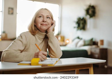 Mature woman writes in her diary sitting at a desk in her room at Christmas home. Thinks about plans, keeps a diary. - Powered by Shutterstock