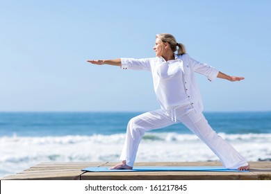 Mature Woman Yoga Exercise On Beach 