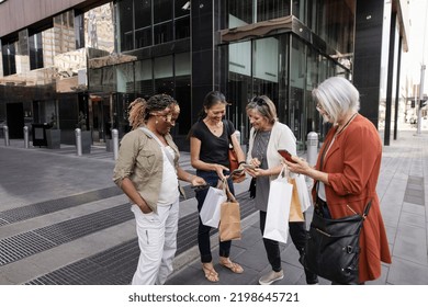 Mature women friends shopping and using smart phones in city - Shutterstock ID 2198645721