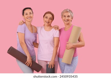 Mature women with yoga mats on pink background - Powered by Shutterstock