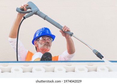 Mature Worker With Safety Gear Using A Pressure Washer