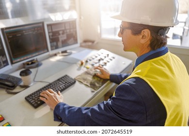 Matured Man Factory Operator Sitting At The Table And Working On Desktop Computer