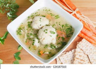 Matzah Ball Soup garnished with carrots and Matzo crackers