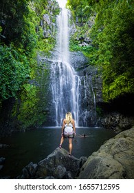 Maui, Hawaii Hana Highway, Sexy blonde girl admires Wailua Falls, near Lihue, Kauai. Road to Hana connects Kahului to the town of Hana Over 59 bridges, 620 curves, tropical rainforest.