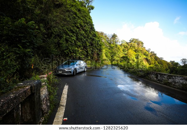 Maui, Hawaii / USA - November 5, 2018: A\
rental car is stopped on the side of the famous Road to Hana near a\
trail leading to a waterfall.\
