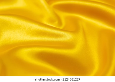 Mauled gold-colored glossy fabric texture background. This fabric is made of 100% polyester.