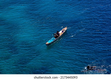 Maumere Flores, Indonesia, June 23, 2022. A fisherman is rowing a wooden boat in the tropical sea of Flores Indonesia with his swimming partner               