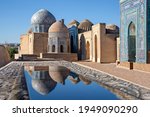 Mausoleums and domes of the historical cemetery of Shahi Zinda and their reflections in puddle, Samarkand, Uzbekistan.