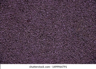 Mauve background from rubber coating of a sports ground. Recycled rubber tires are cut into small pieces, glued and painted in purple