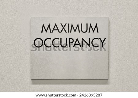 Maximum Occupancy sign on a white interior wall in a commercial building. An NFPA Fire Marshal requirement to safeguard buildings from overcrowding.