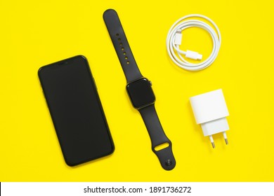 May 01, 2020, Rostov, Russia: Smartphone iPhone, Apple Watch S4, charger, USB-C cable, Lightning lie diagonally on yellow background, top view, copy space for advertising text